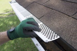 A person installing a leaf guard on a gutter.