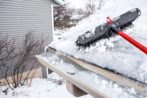 frozen gutters on a house with a roof rake next to them