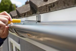 a person tightening loose gutters