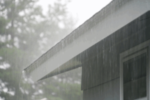 a close-up of a house with gutters during heavy rainfall